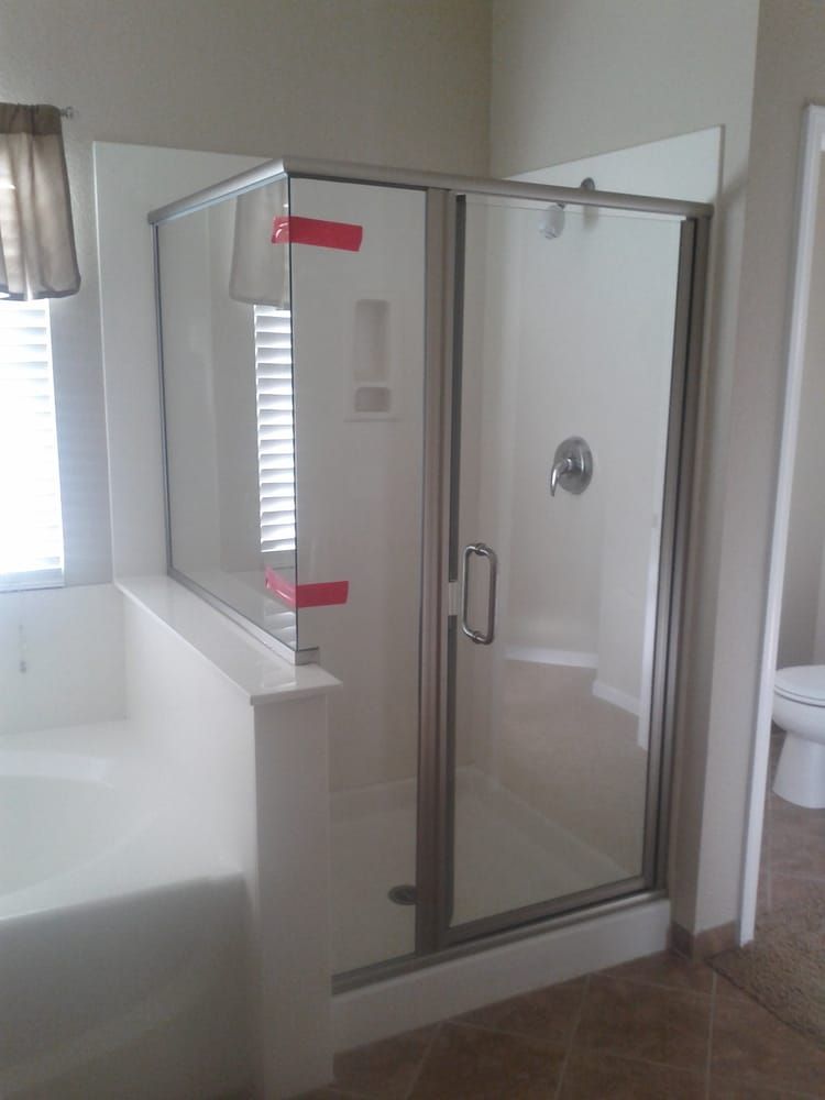 A bathroom with a walk in shower , tub , toilet and window.
