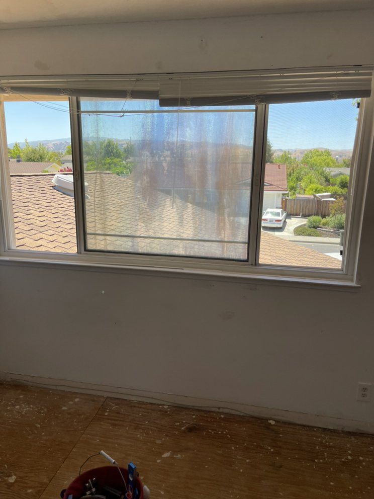 A room with a window and a bucket on the floor.