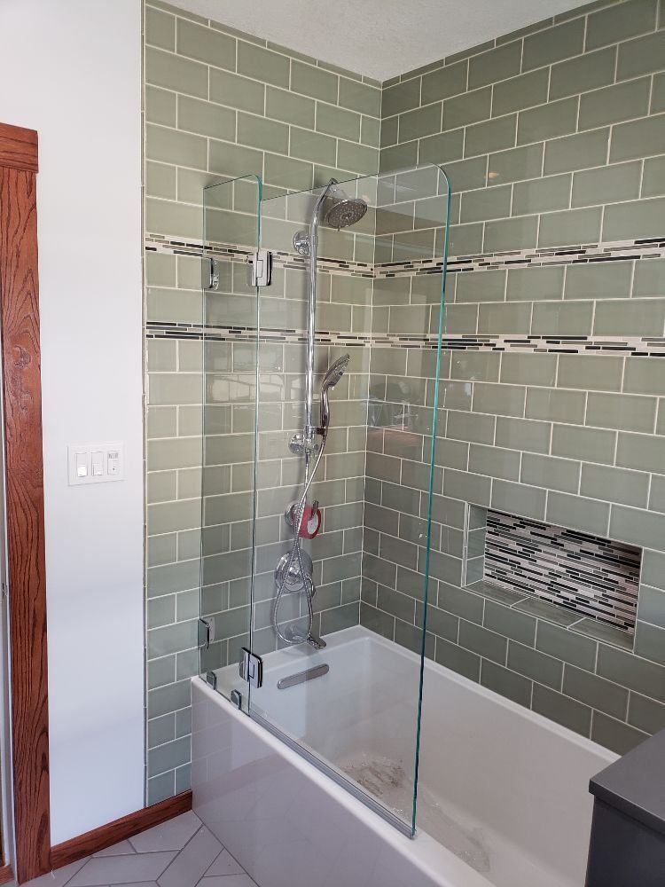 A bathroom with a bathtub and a glass shower door.