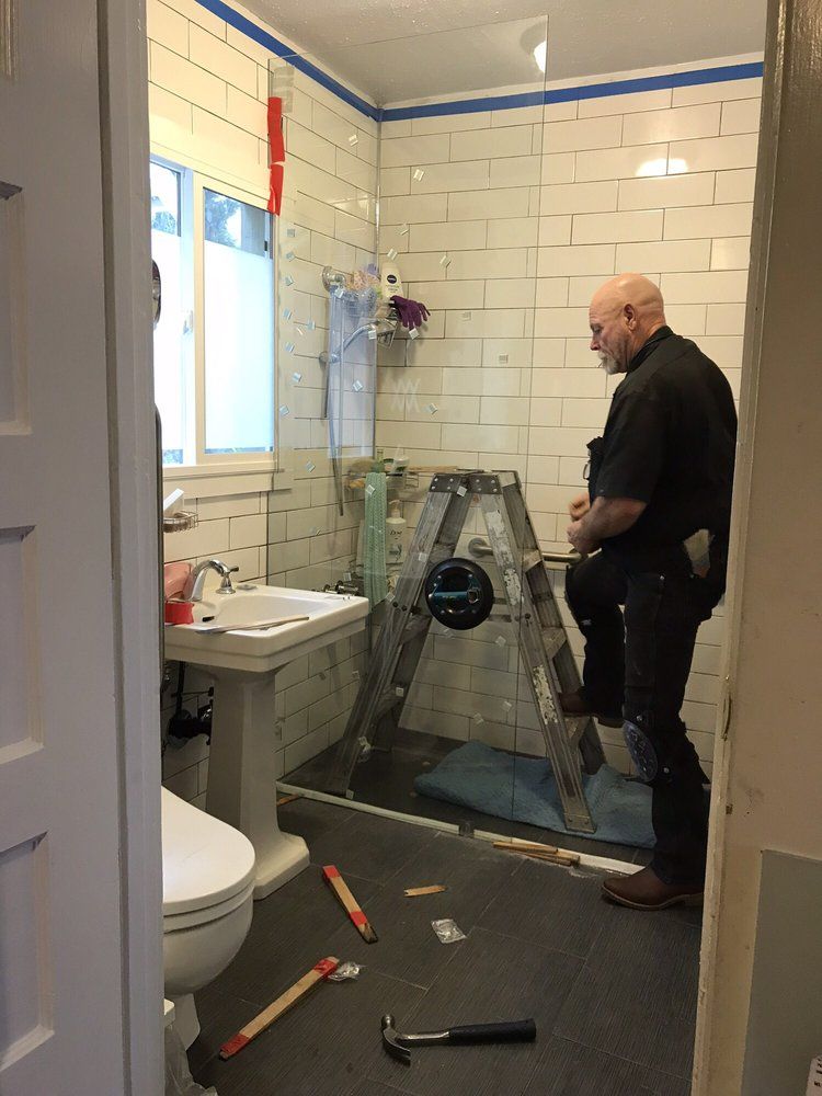 A man is standing in a bathroom with a ladder.