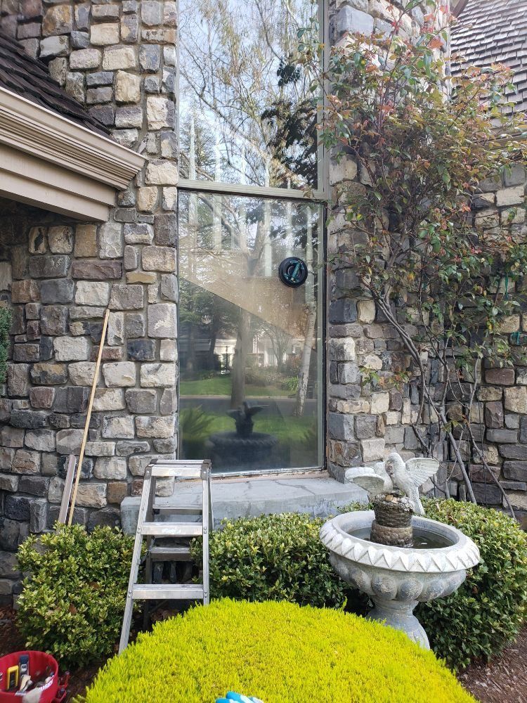 A ladder is sitting in front of a stone building next to a fountain.