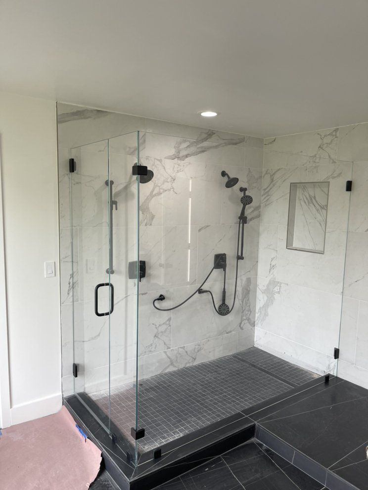 A bathroom with a walk in shower with a glass door.