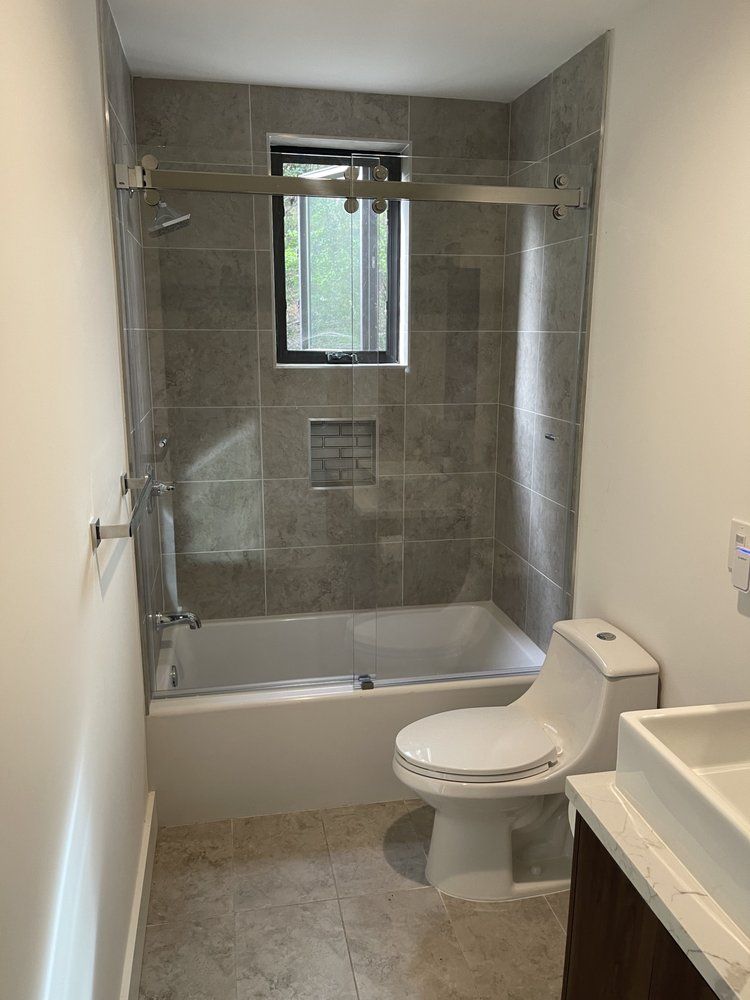 A bathroom with a toilet , sink , tub and shower.