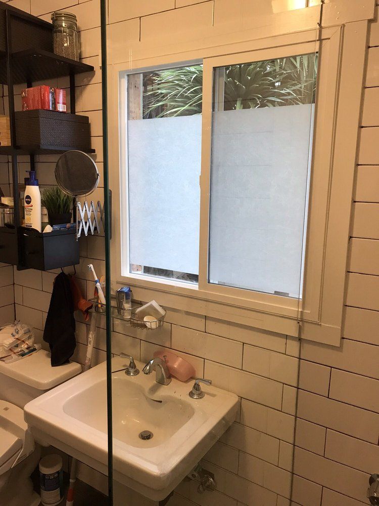 A bathroom with a sink , toilet , mirror and window