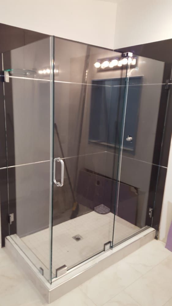 A bathroom with a glass shower stall and a window.