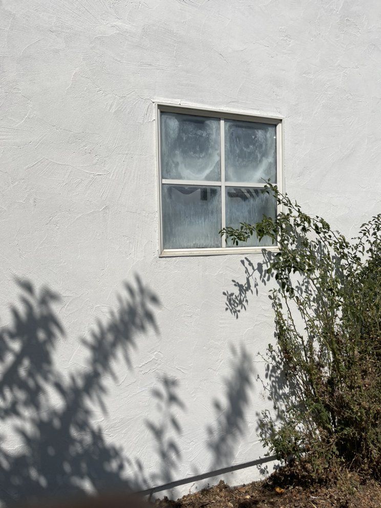 A white wall with a window and shadows on it