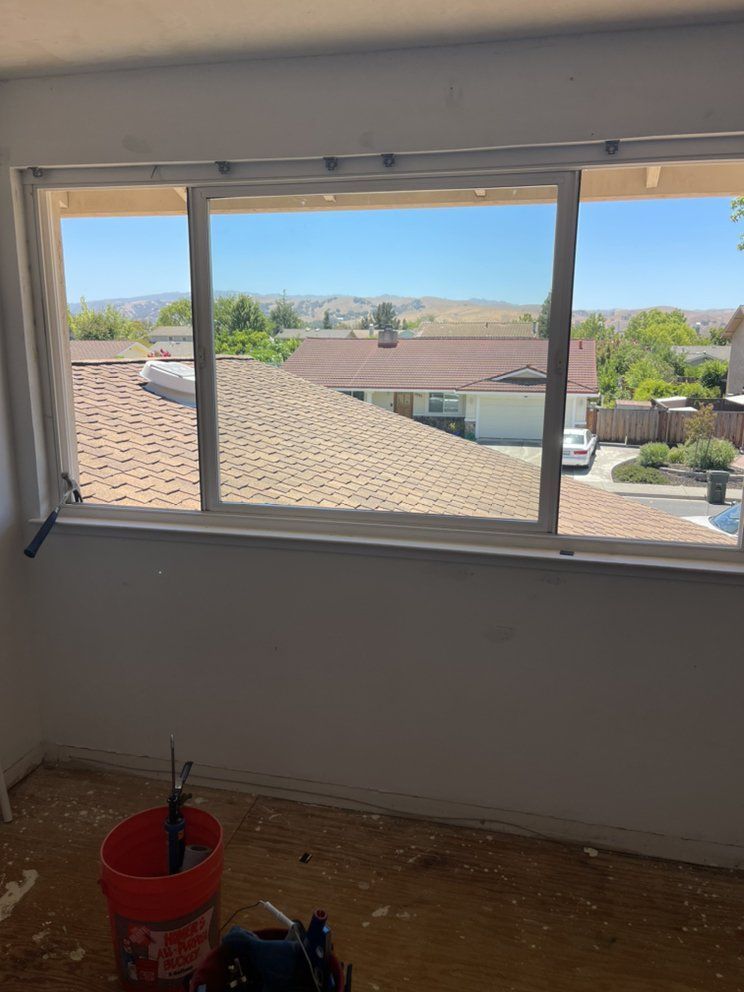 A room with a window and a bucket of water on the floor.