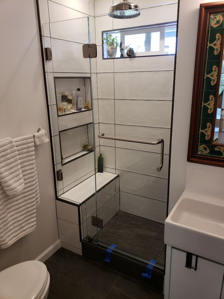 A bathroom with a walk in shower , toilet , sink and mirror.