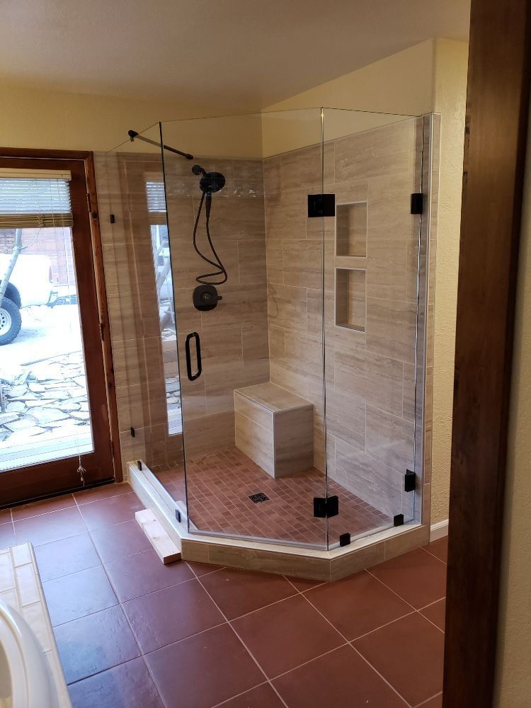 A bathroom with a walk in shower with a bench.