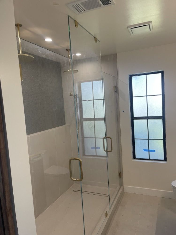 A bathroom with a glass shower door and a window.