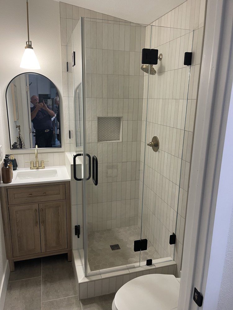 A bathroom with a walk in shower , sink , toilet and mirror.