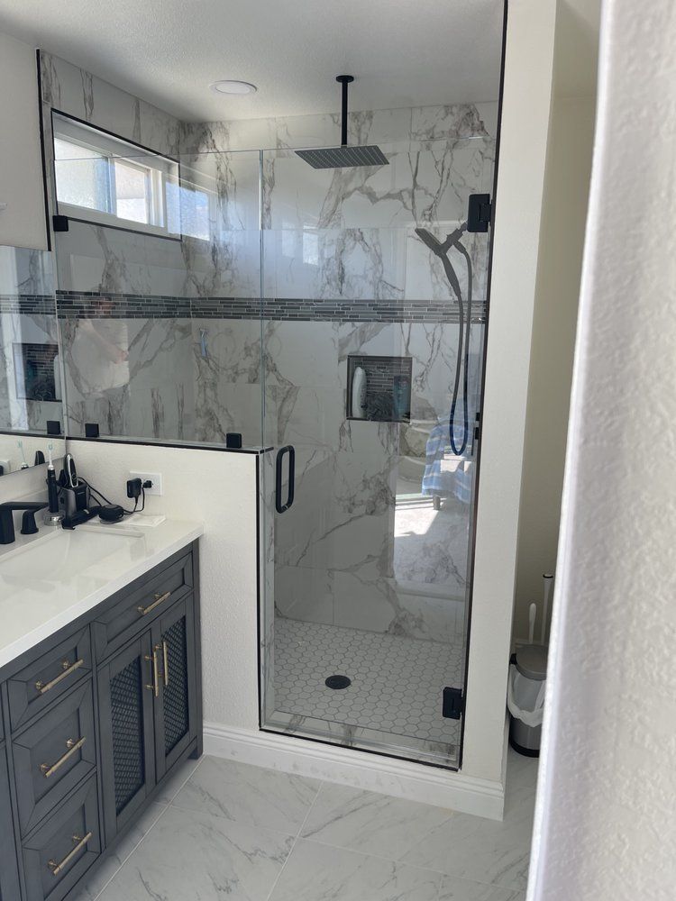 A bathroom with a walk in shower and a sink.