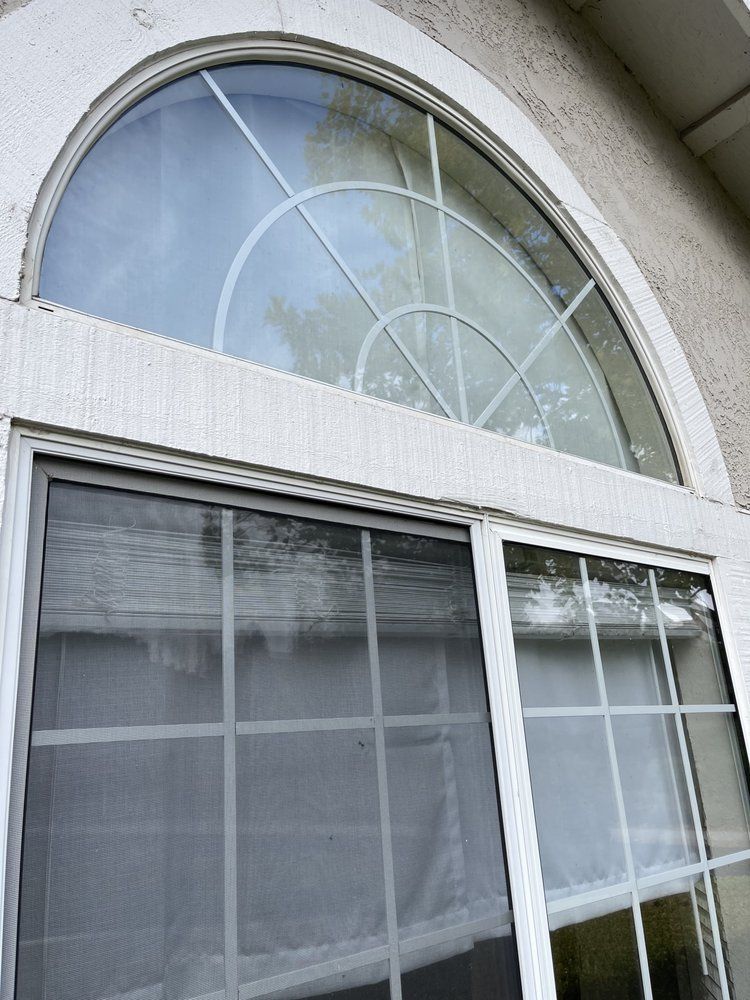 A large arched window with a sliding screen door