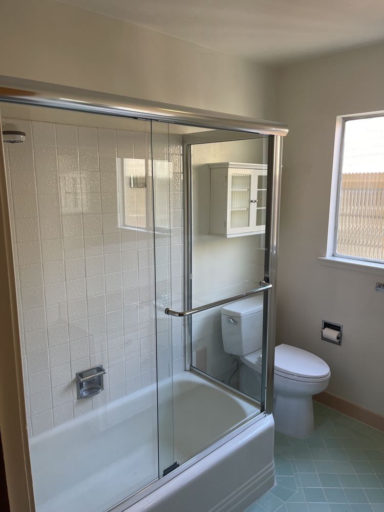 A bathroom with a toilet , tub , shower and window.