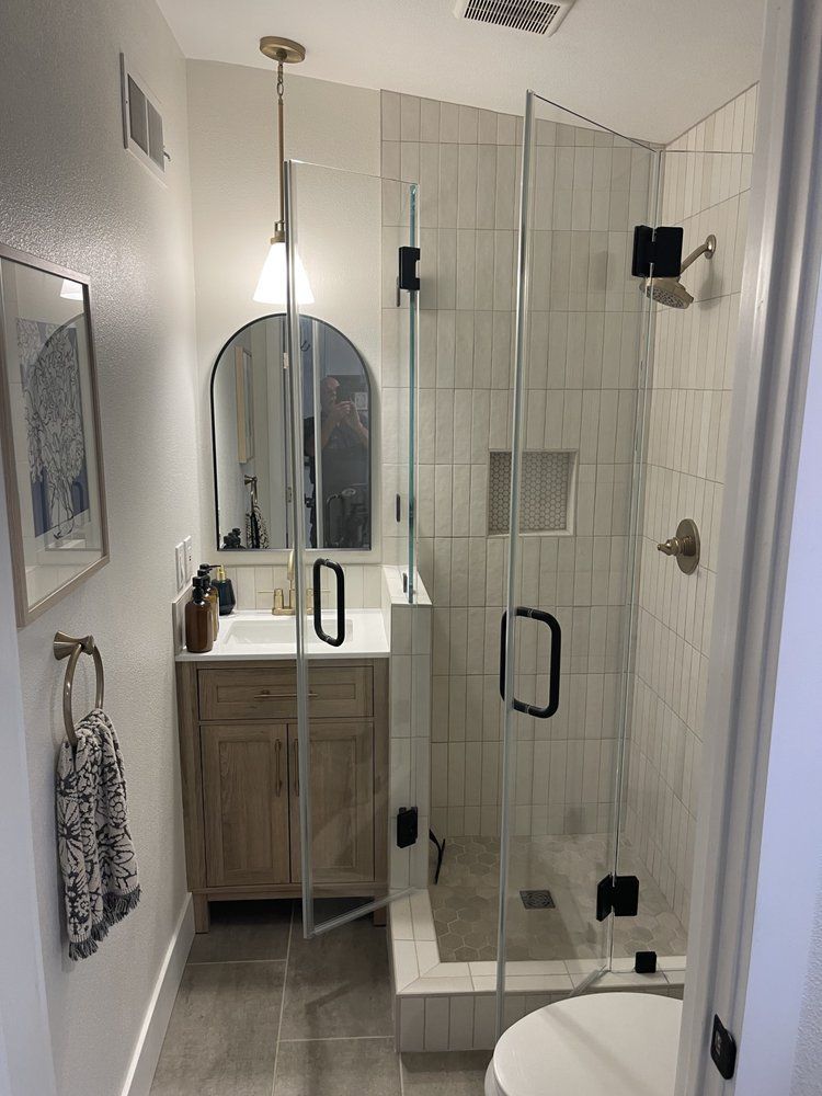 A bathroom with a walk in shower , sink , toilet and mirror.