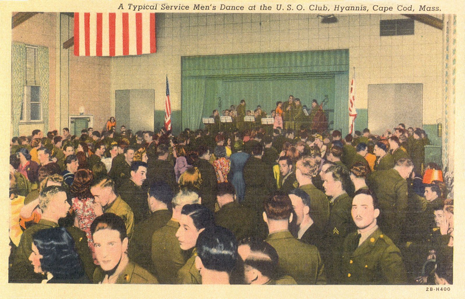 A large group of people in military uniforms are gathered in front of a stage