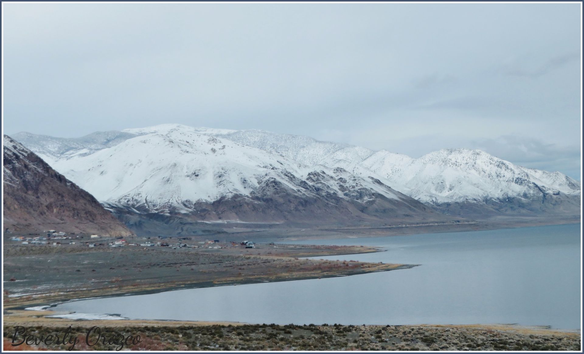 A lake surrounded by snow covered mountains on a cloudy day