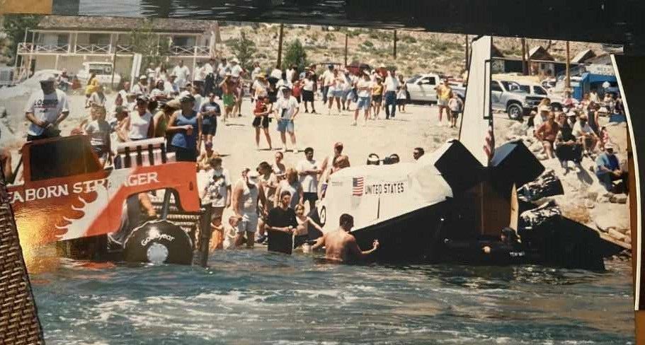 A group of people are gathered around a boat that says aburn on it