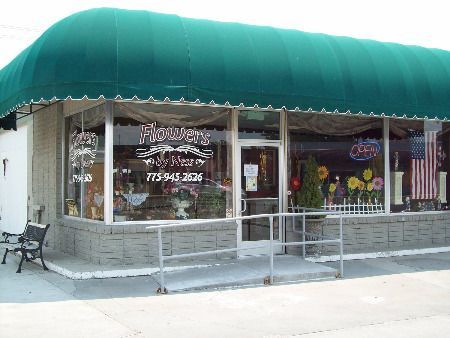 A store front with a green awning that says flowers