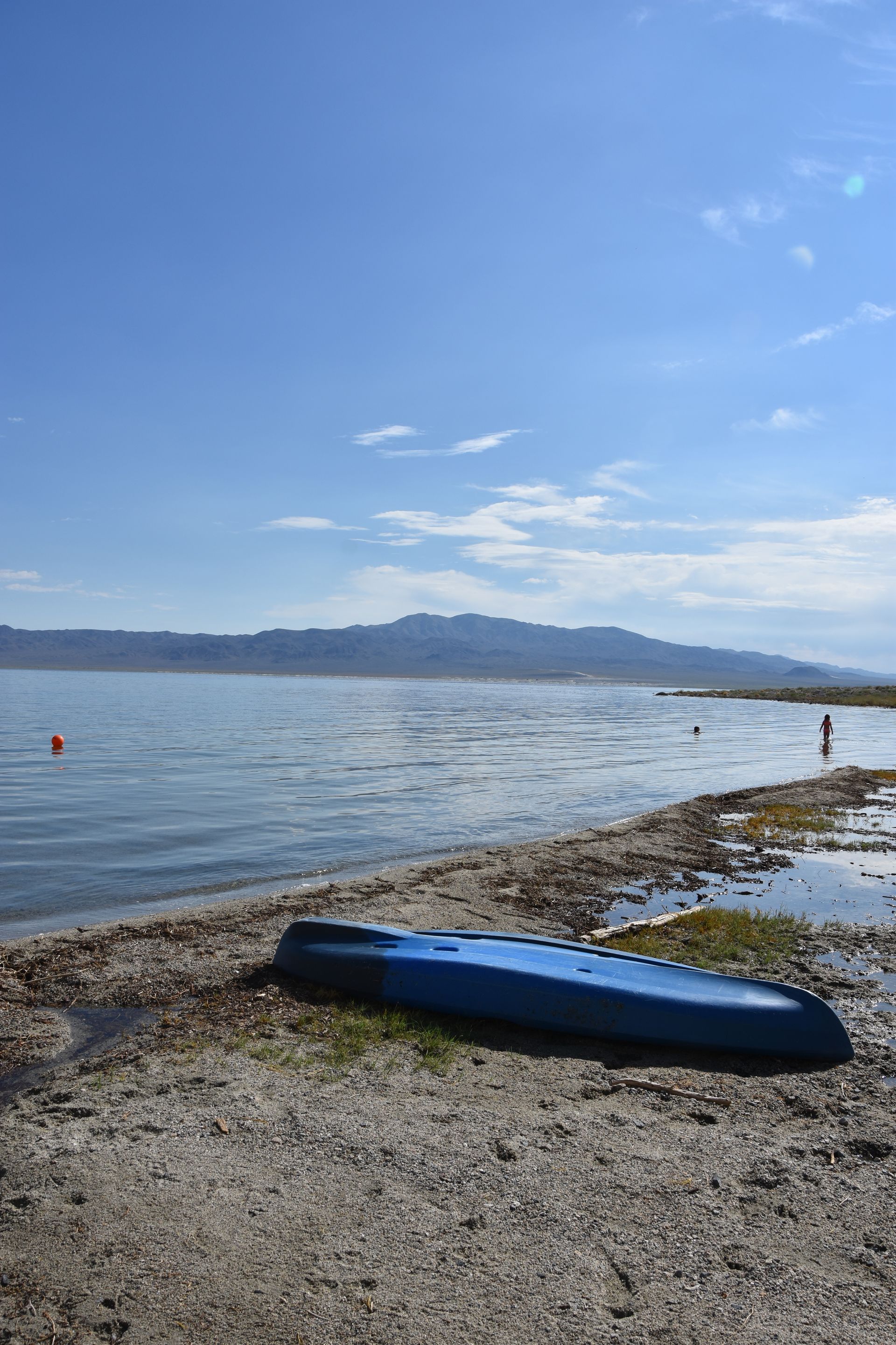 A blue kayak is sitting on the shore of a lake.