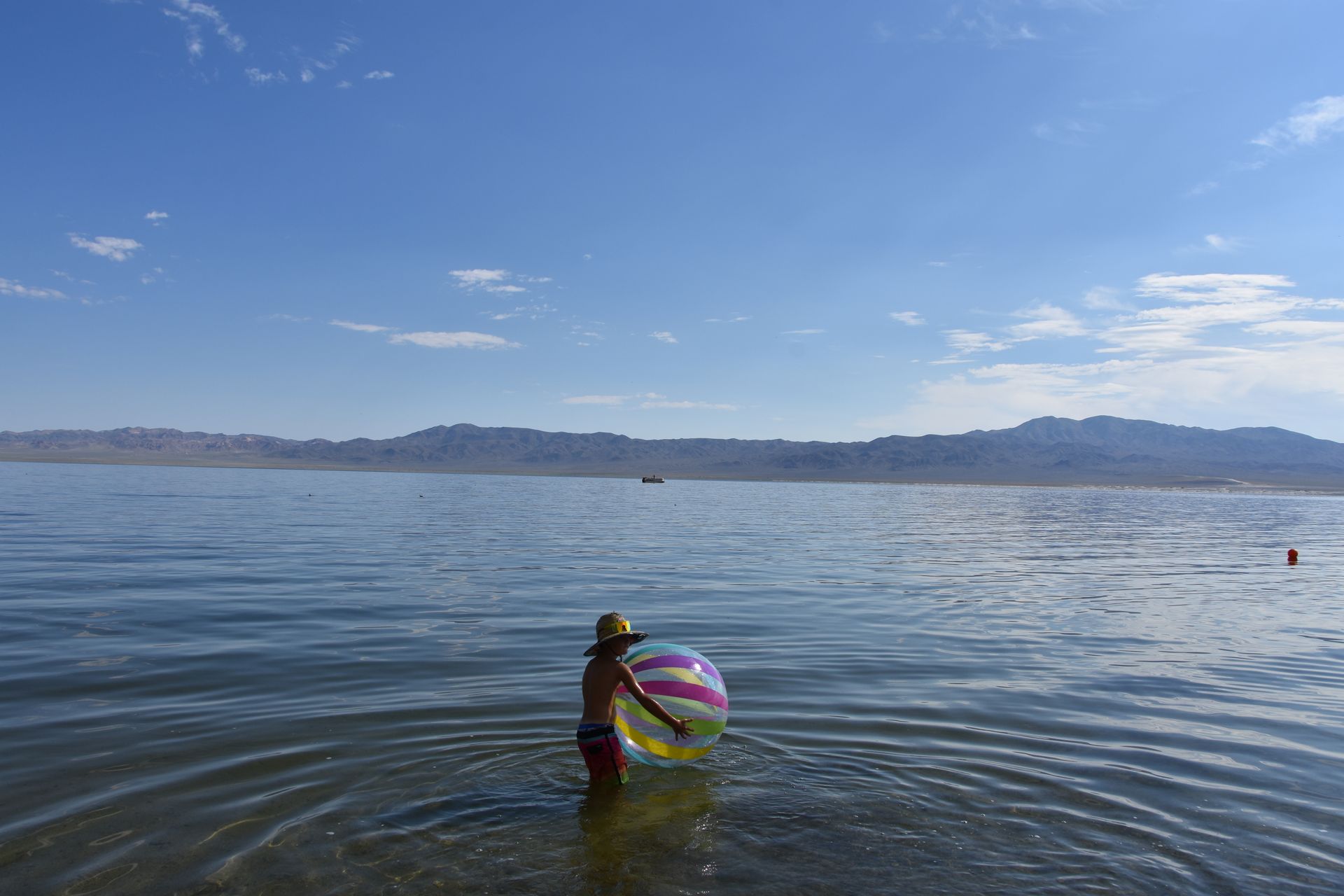 A person is standing in the water holding a beach ball.