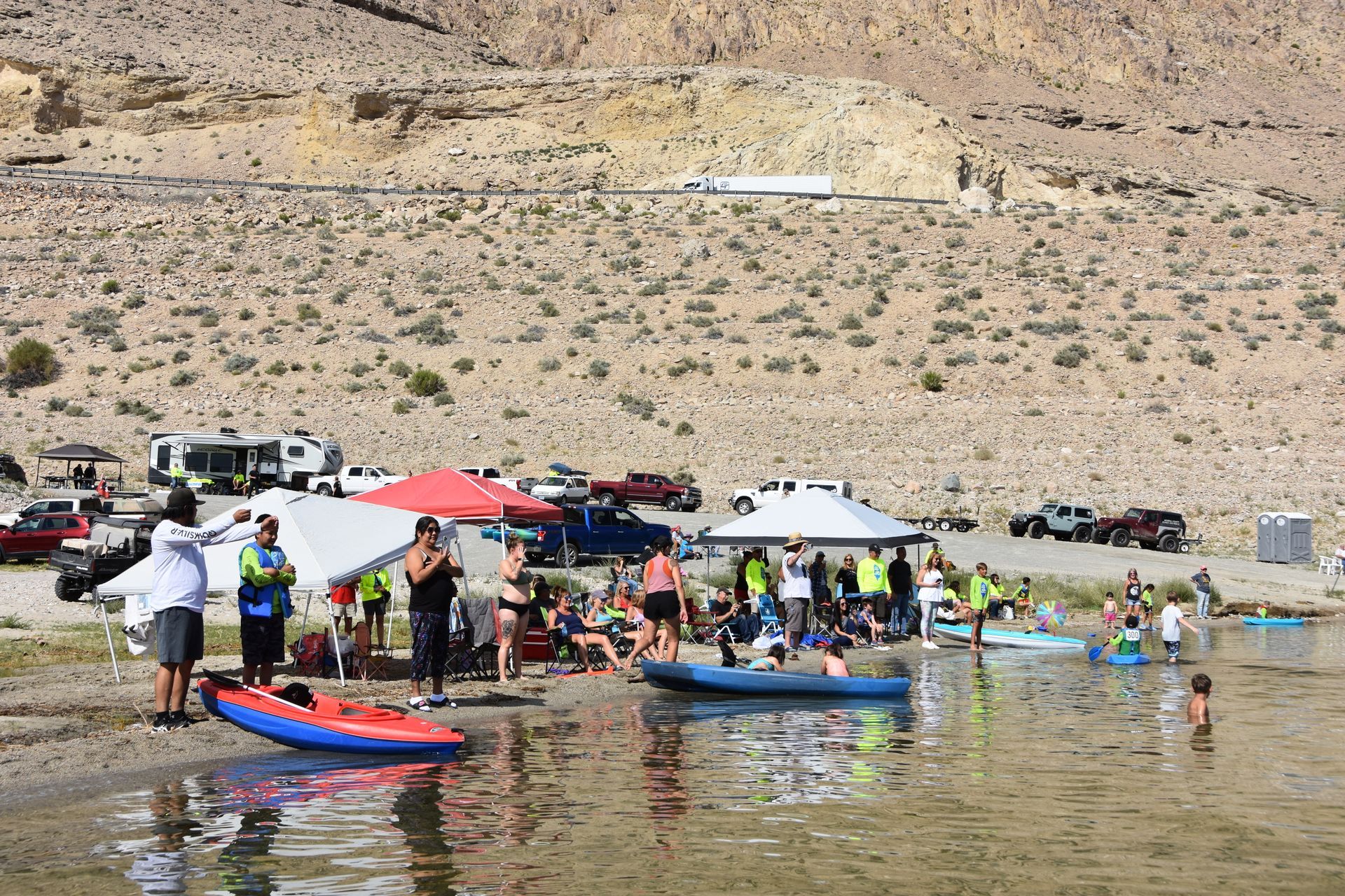 A group of people are standing on the shore of a lake.