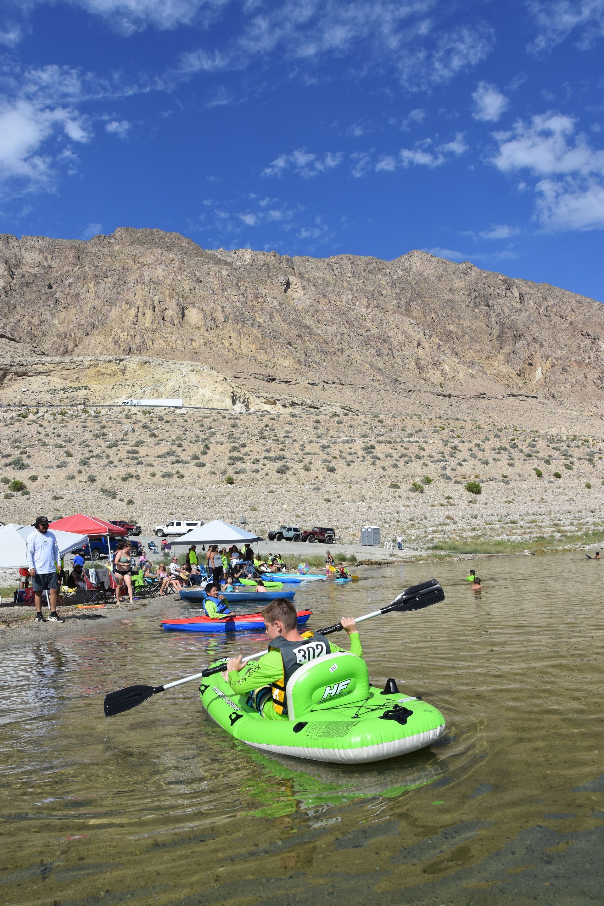 A man is paddling a green kayak in the water.