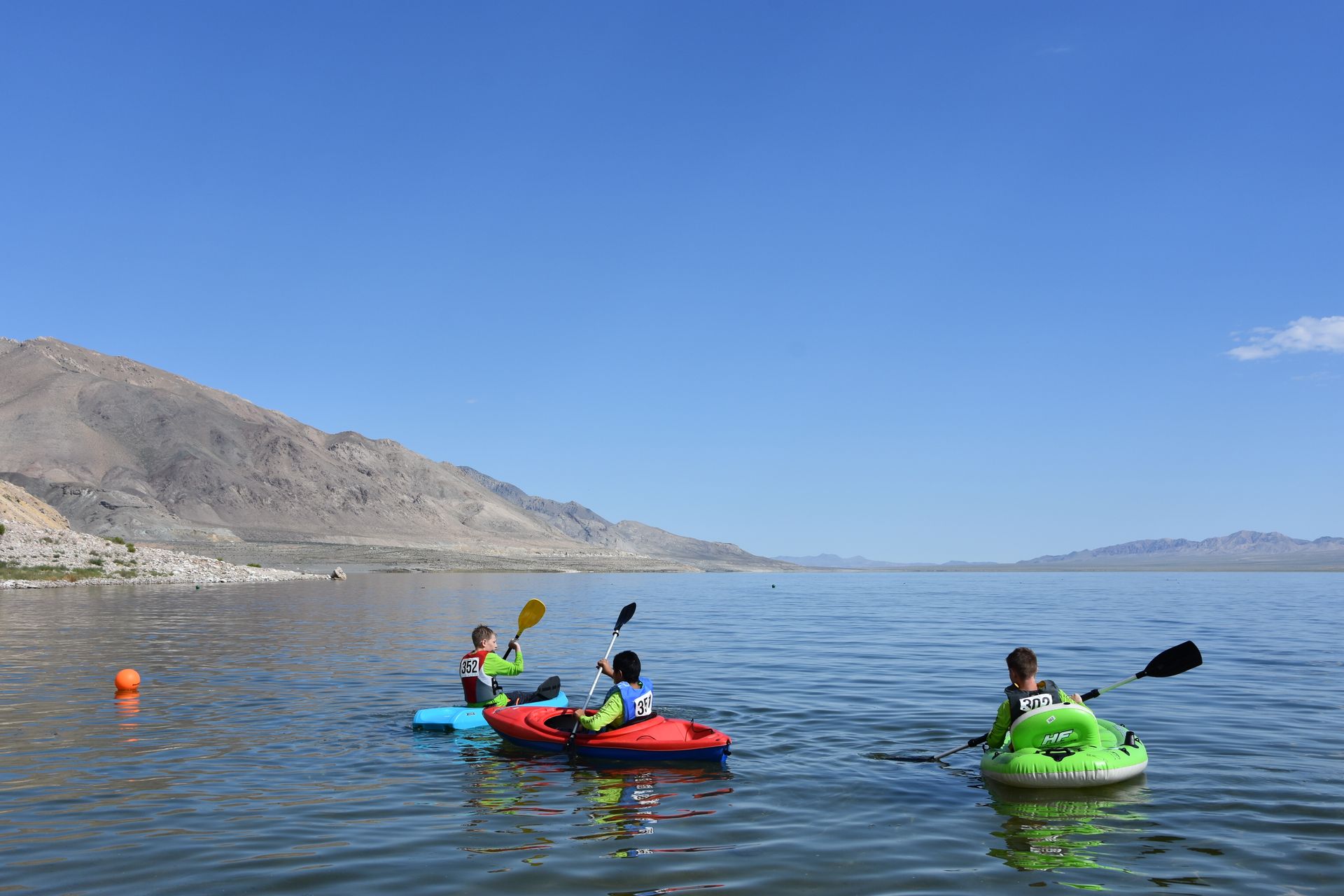 A group of people are kayaking on a lake with mountains in the background.