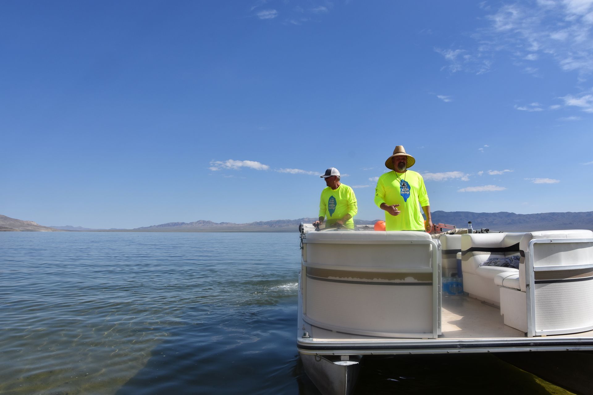 Two men are on a pontoon boat on a lake