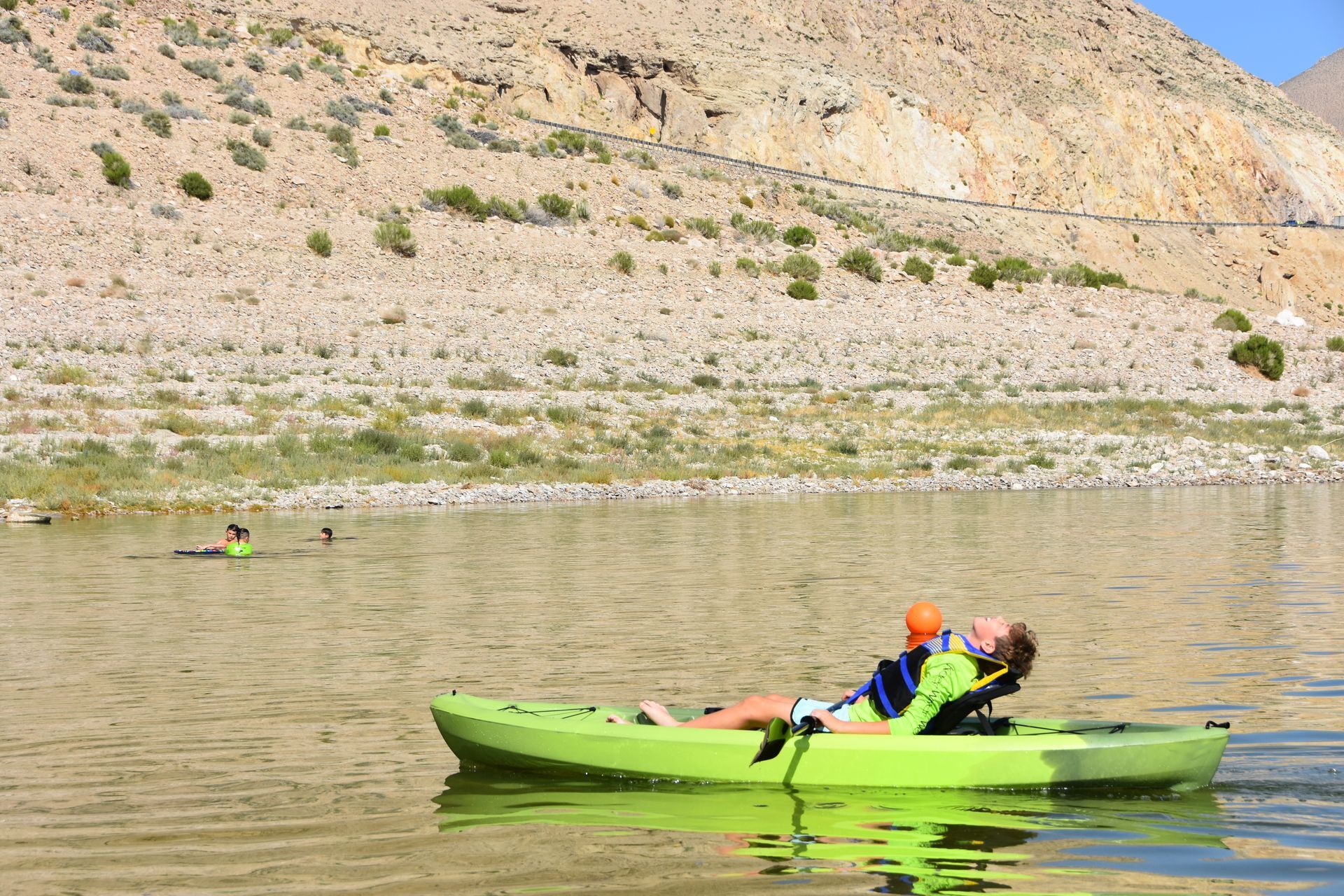 A person is sitting in a green kayak on a lake.