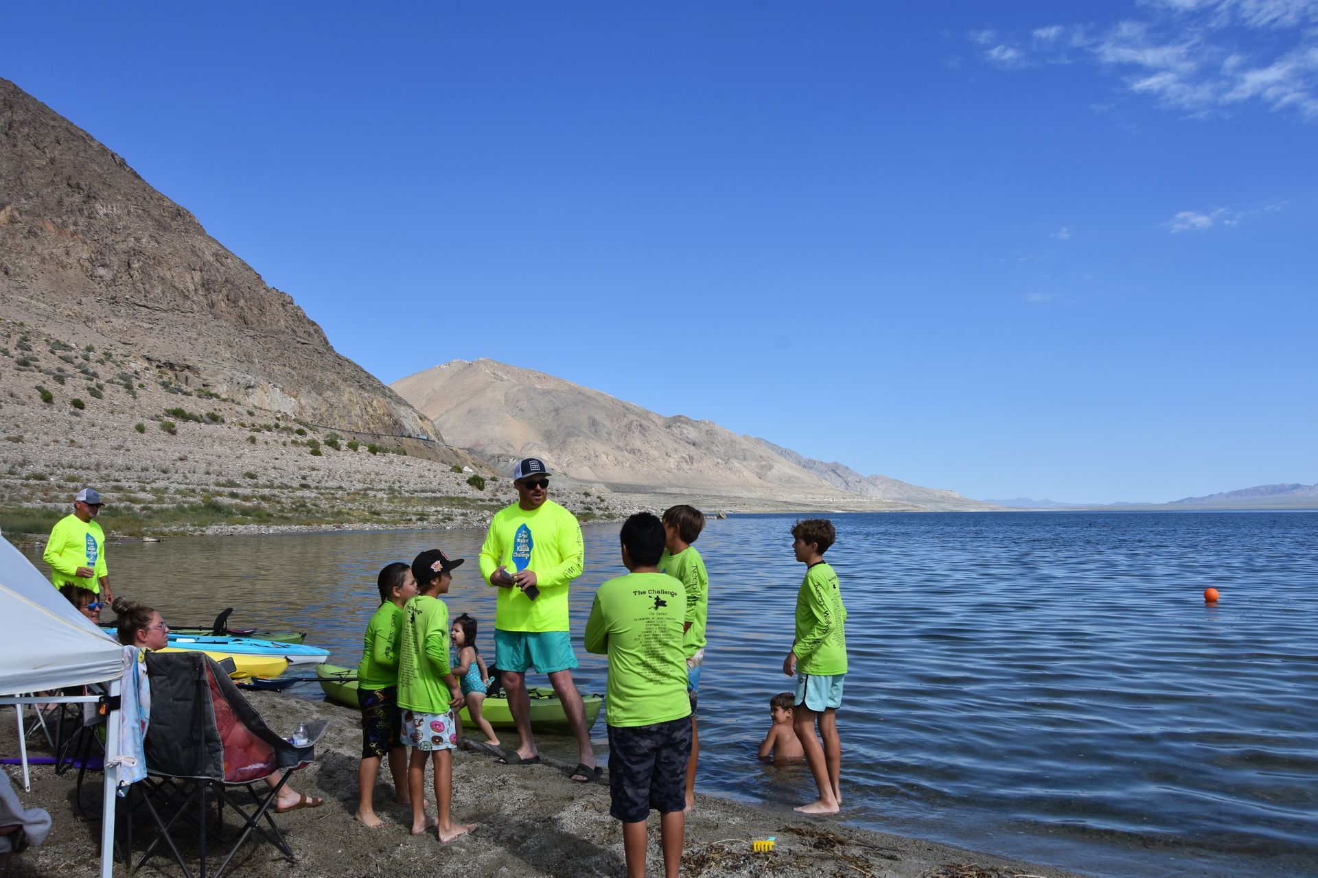 A group of people are standing on the shore of a lake.