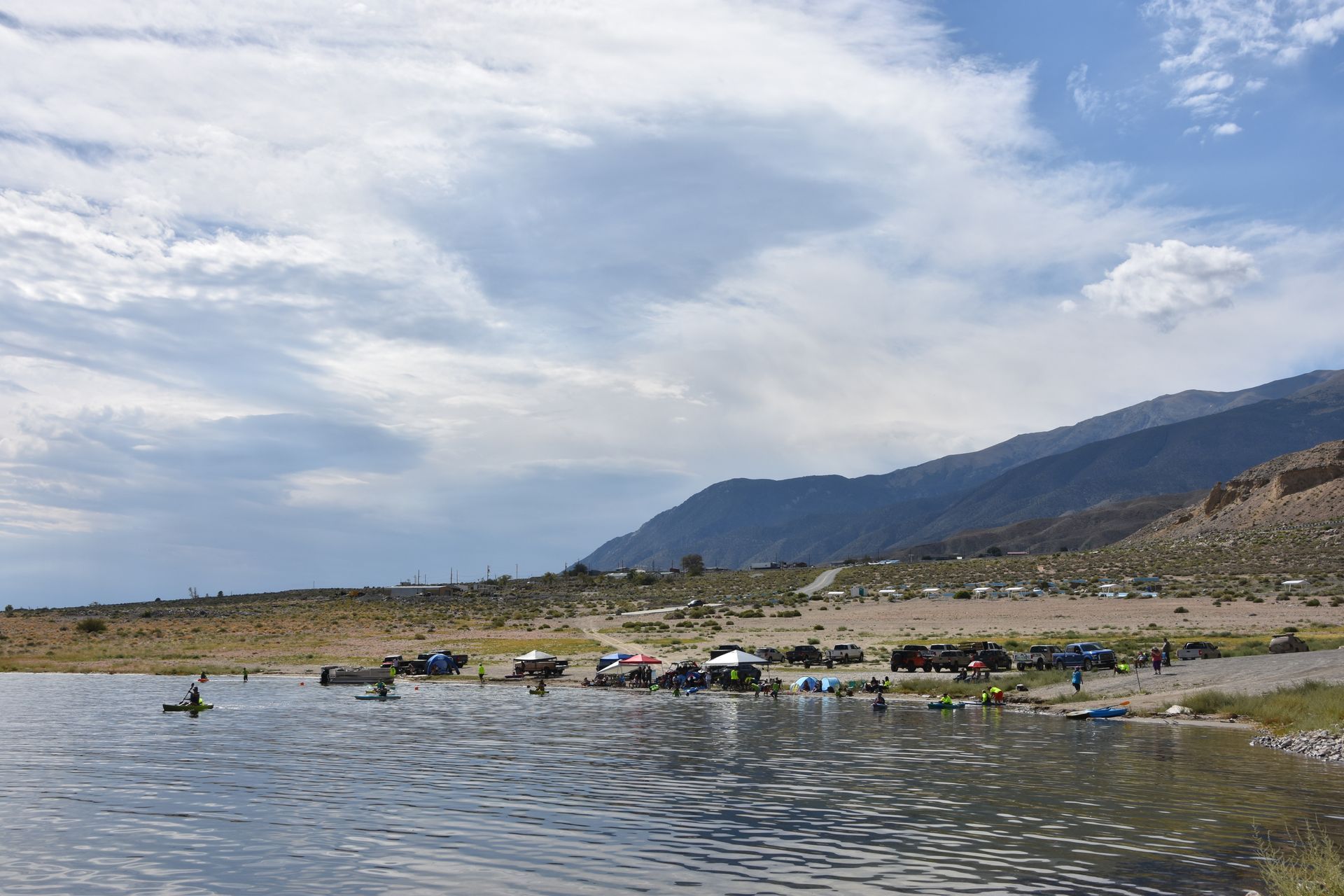 A group of people are swimming in a lake with mountains in the background