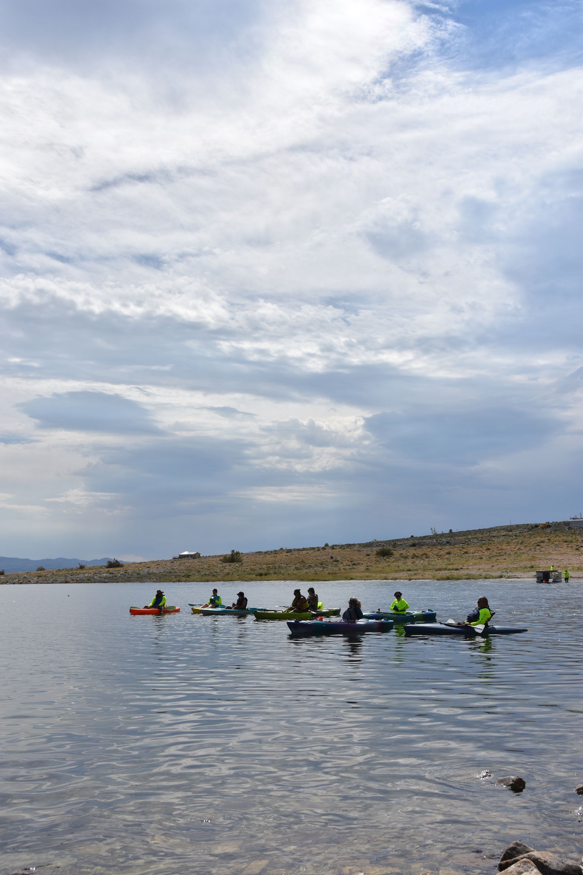 A group of people are rowing kayaks on a lake.