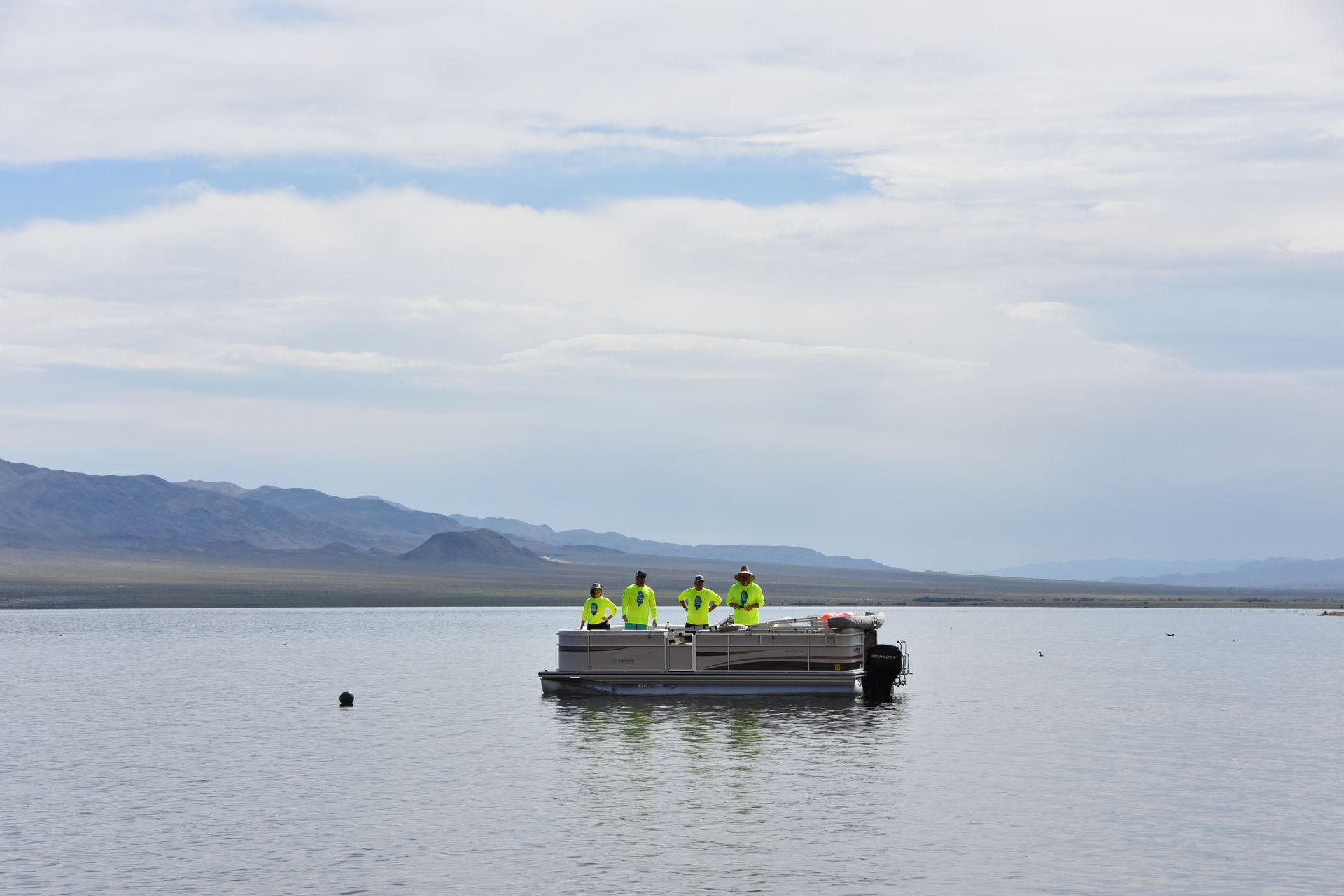 A group of people on a pontoon boat in the middle of a lake