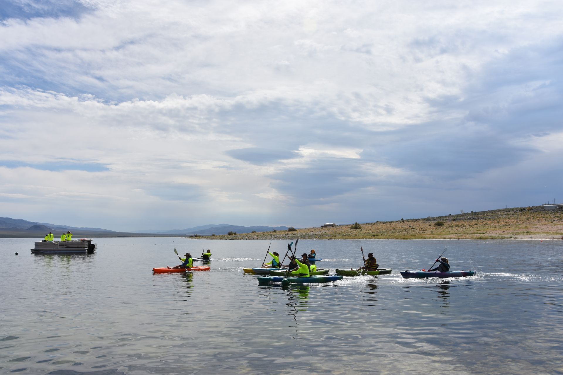 A group of people are rowing kayaks on a lake.