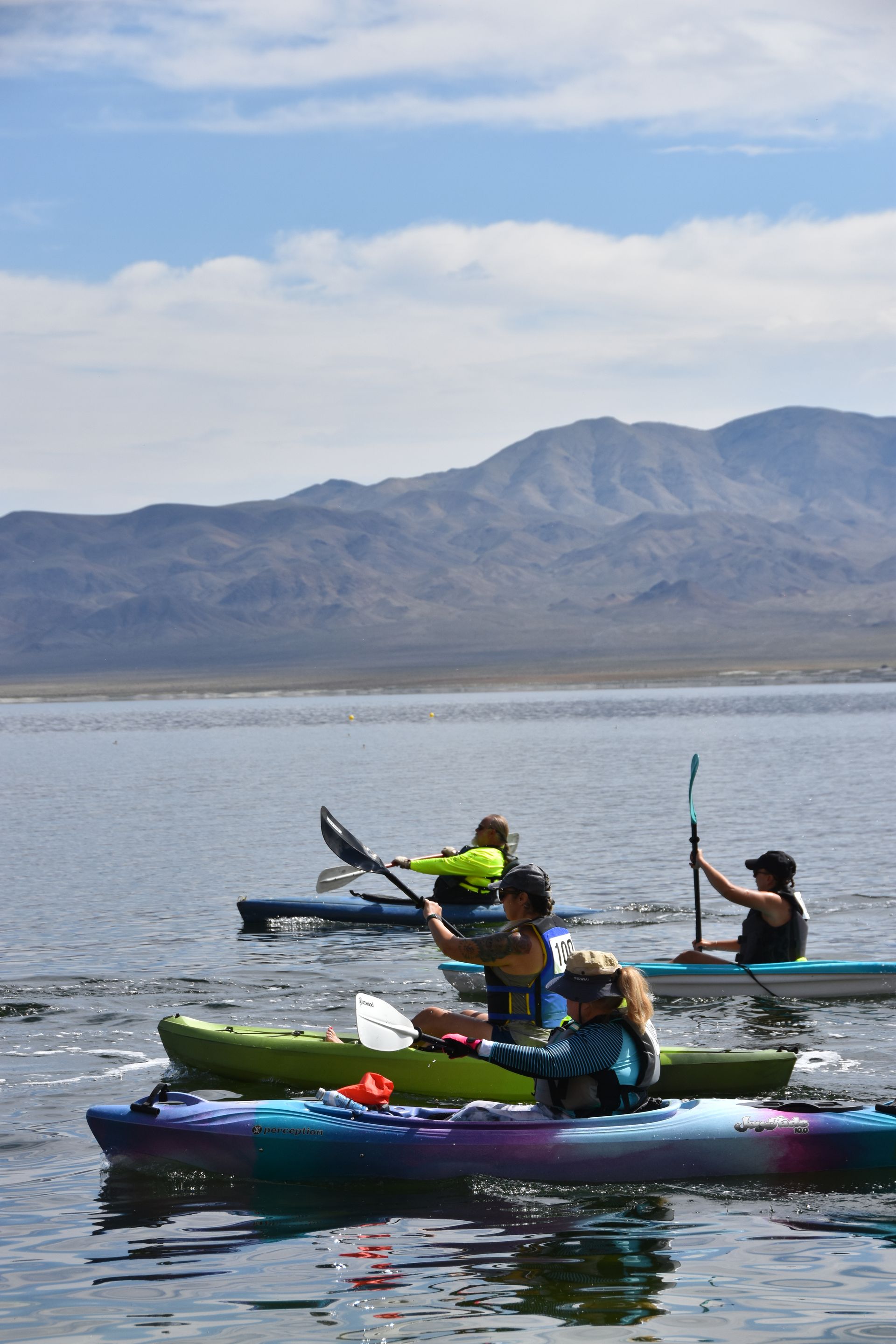 A group of people are rowing kayaks on a lake.