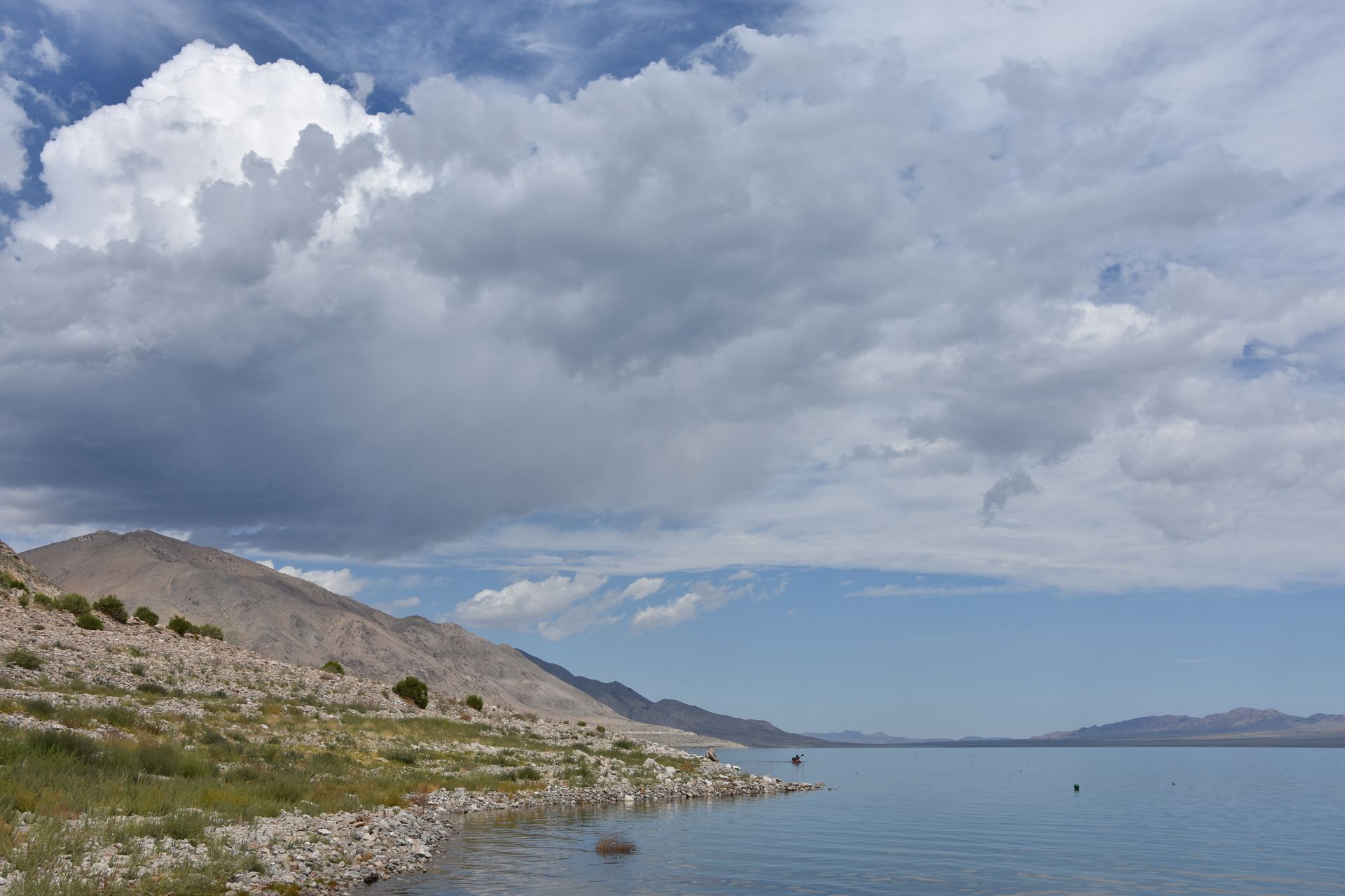 A lake with mountains in the background and clouds in the sky
