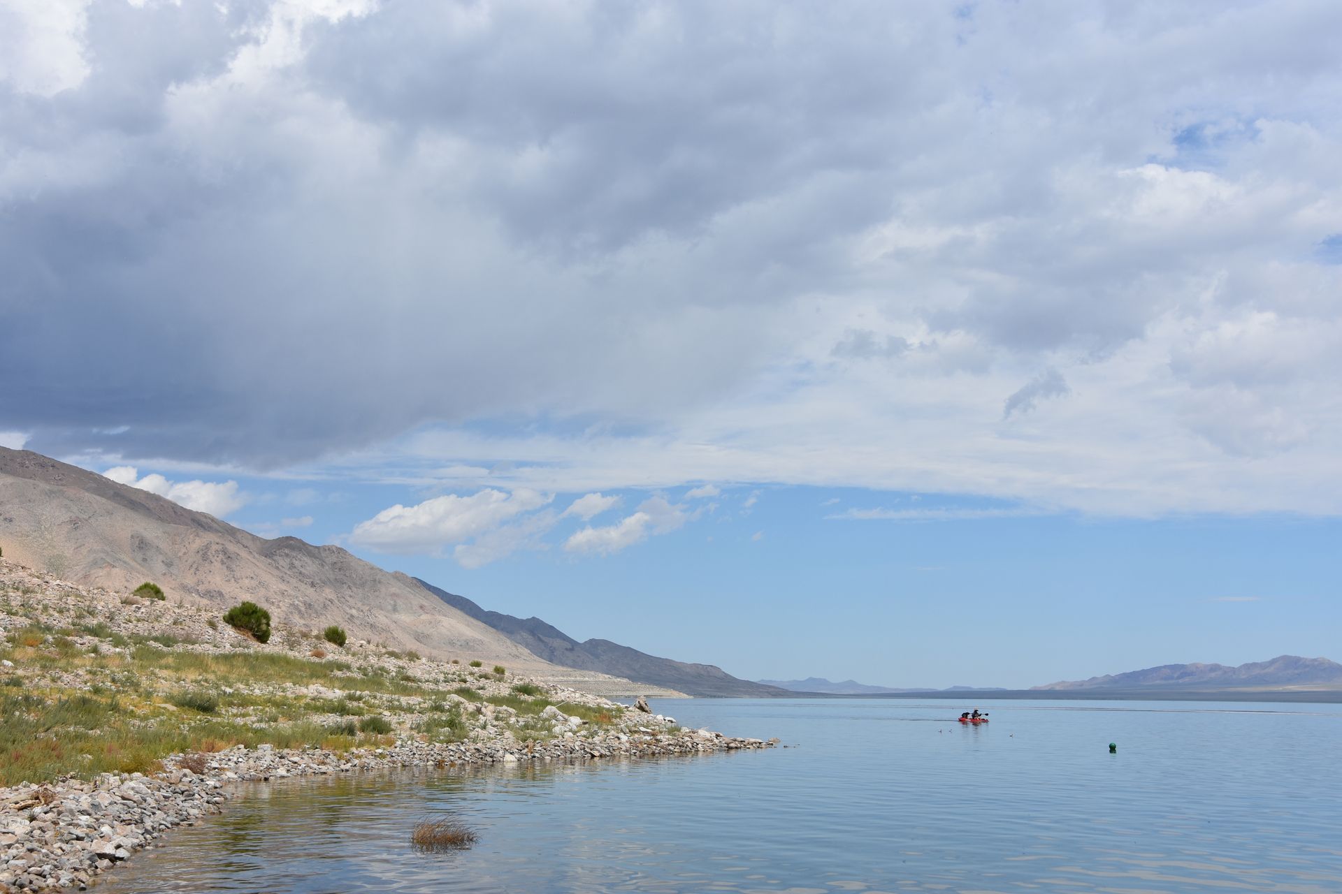 A lake with mountains in the background and a boat in the water.