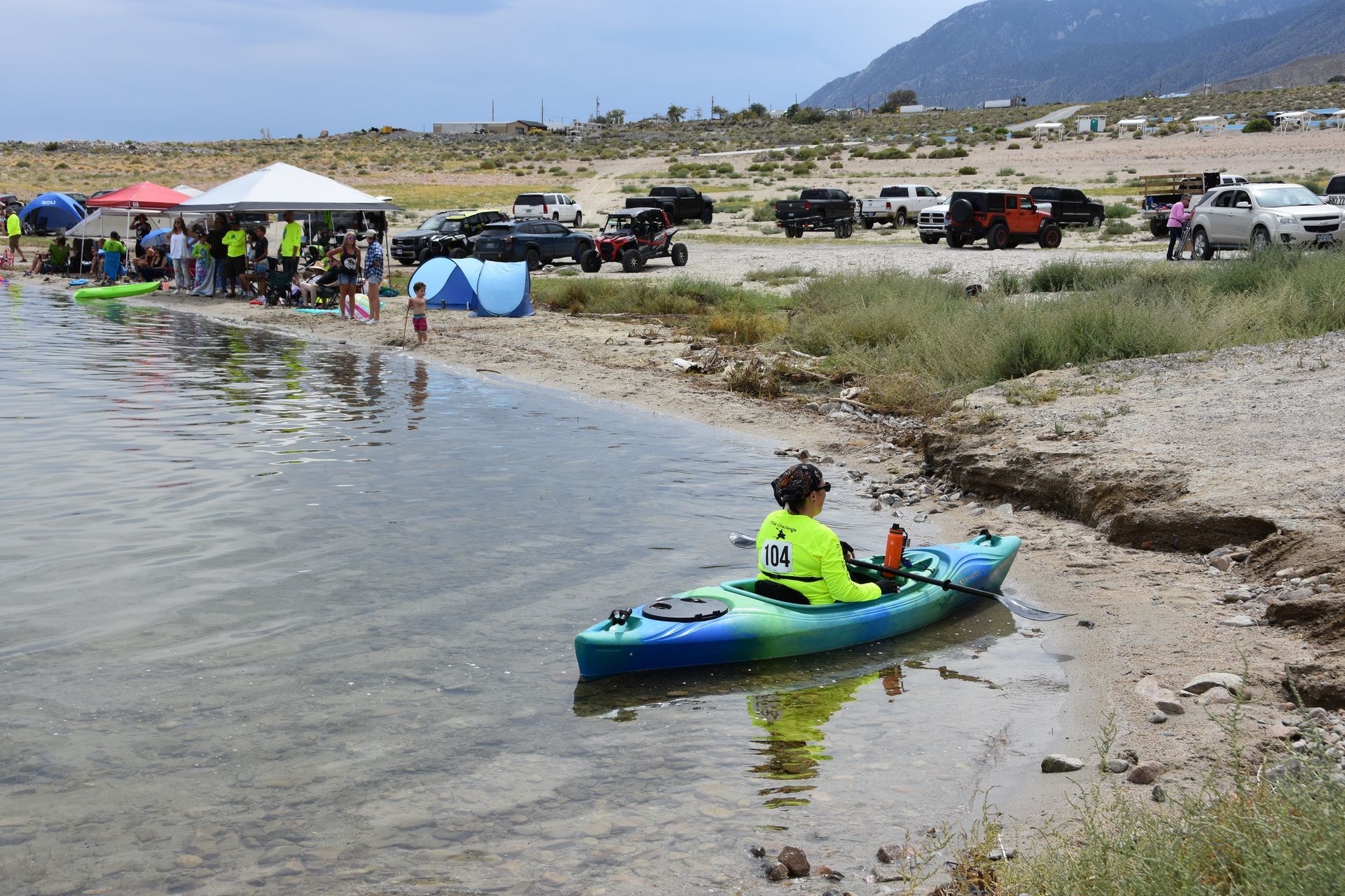 A person in a kayak is sitting on the shore of a lake.