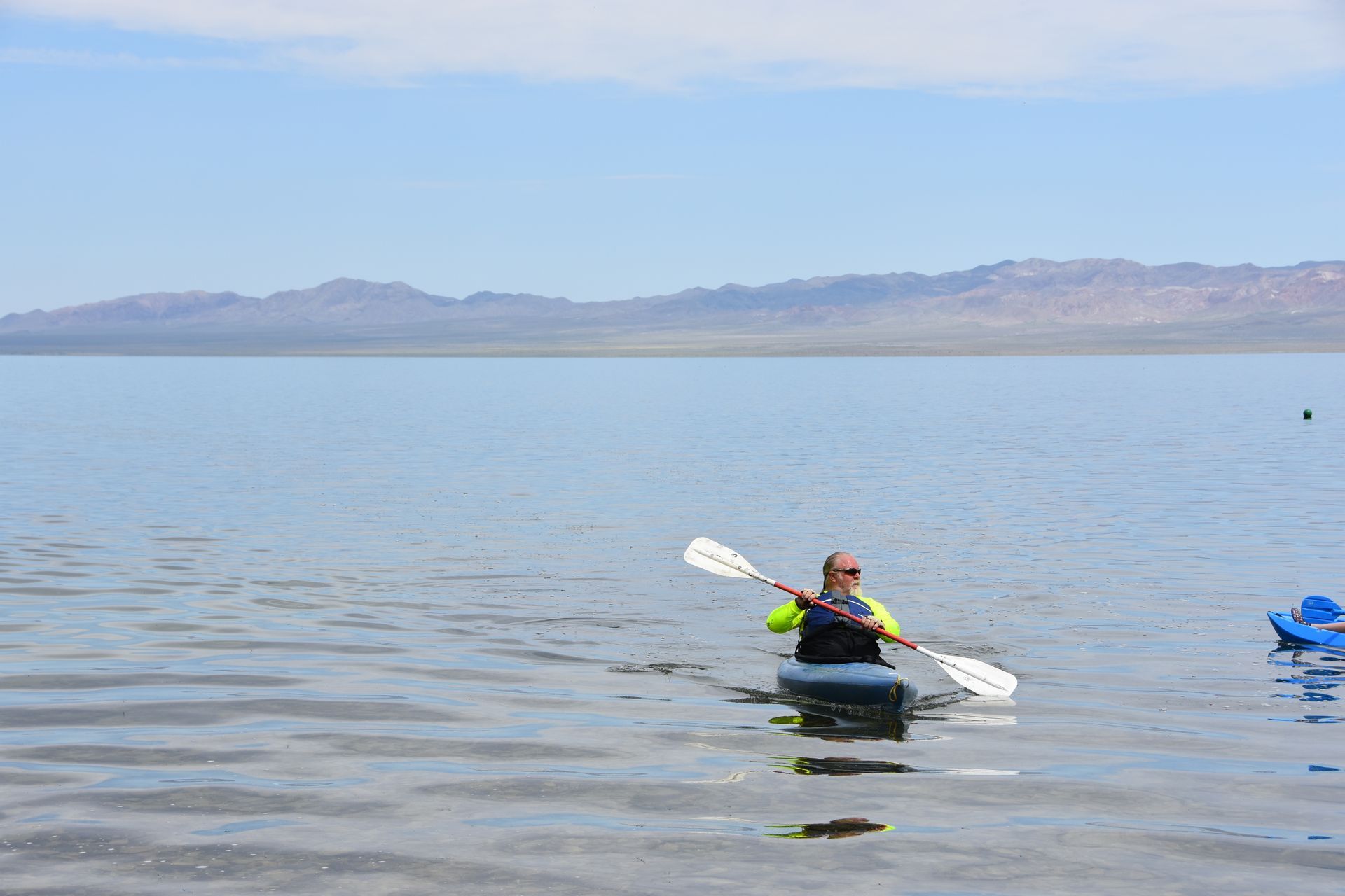 A man is paddling a kayak on a lake.