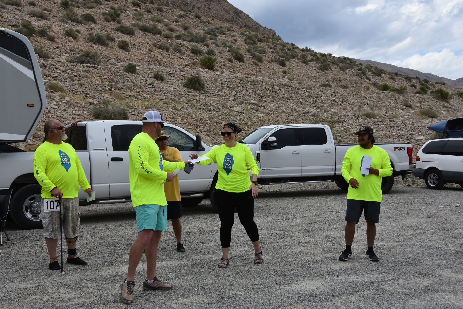 A group of people wearing neon yellow shirts are standing in a parking lot.
