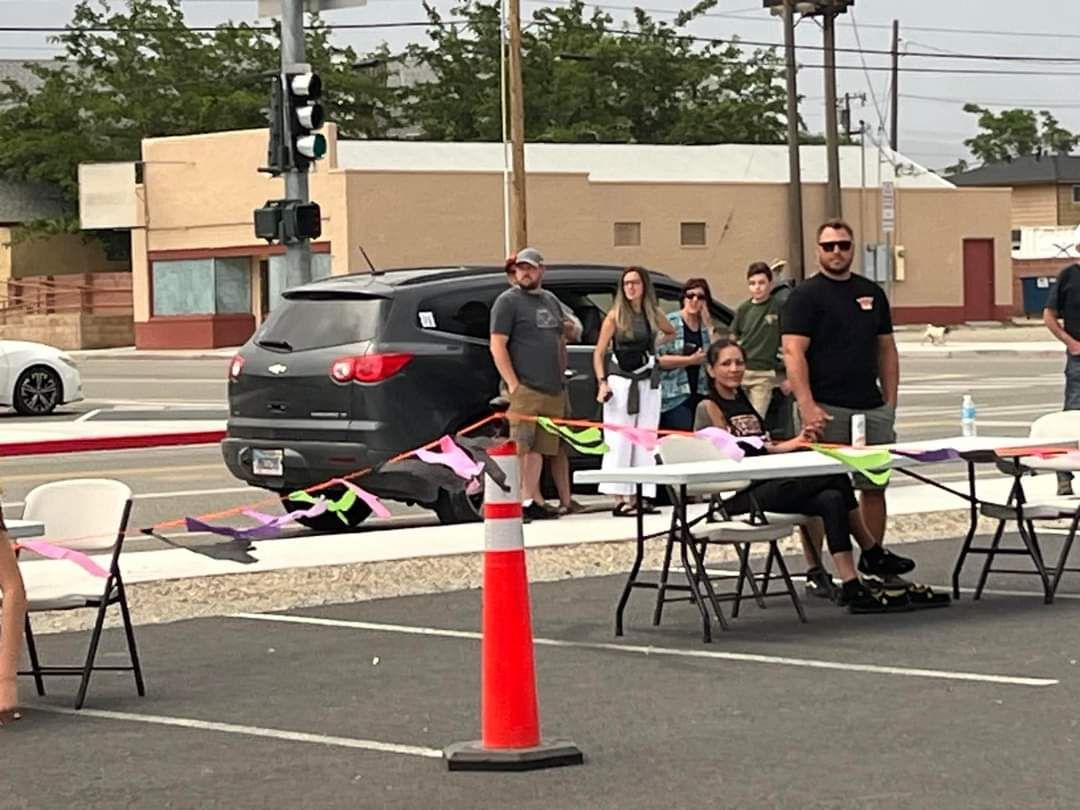 People watching skaters during Hawthorne, NV Skate Night 2024. A table, a black SUV, and traffic lights in the background.
