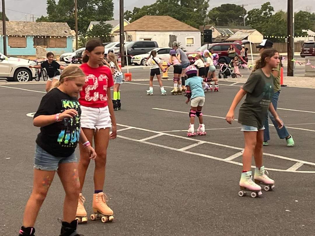 A group of young girls are rollerblading on a street.