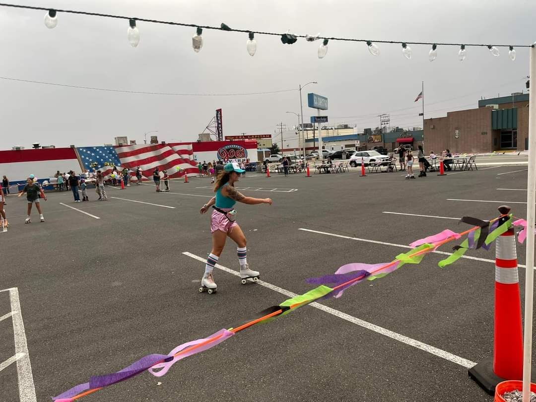 A woman is rollerblading in a parking lot surrounded by colorful ribbons.