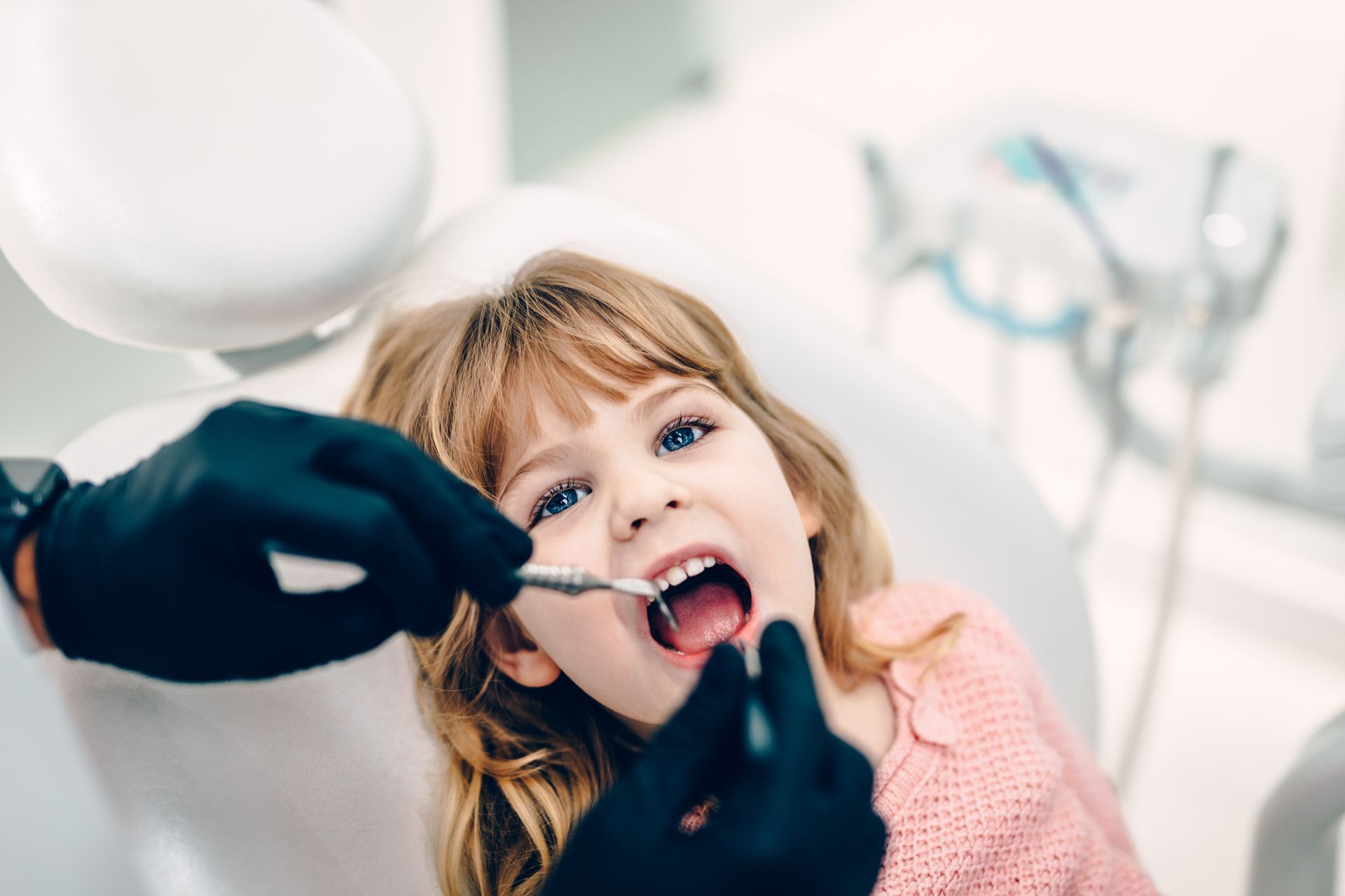 little girl smiling while sitting in dental chair look at the camera ready for her appointment