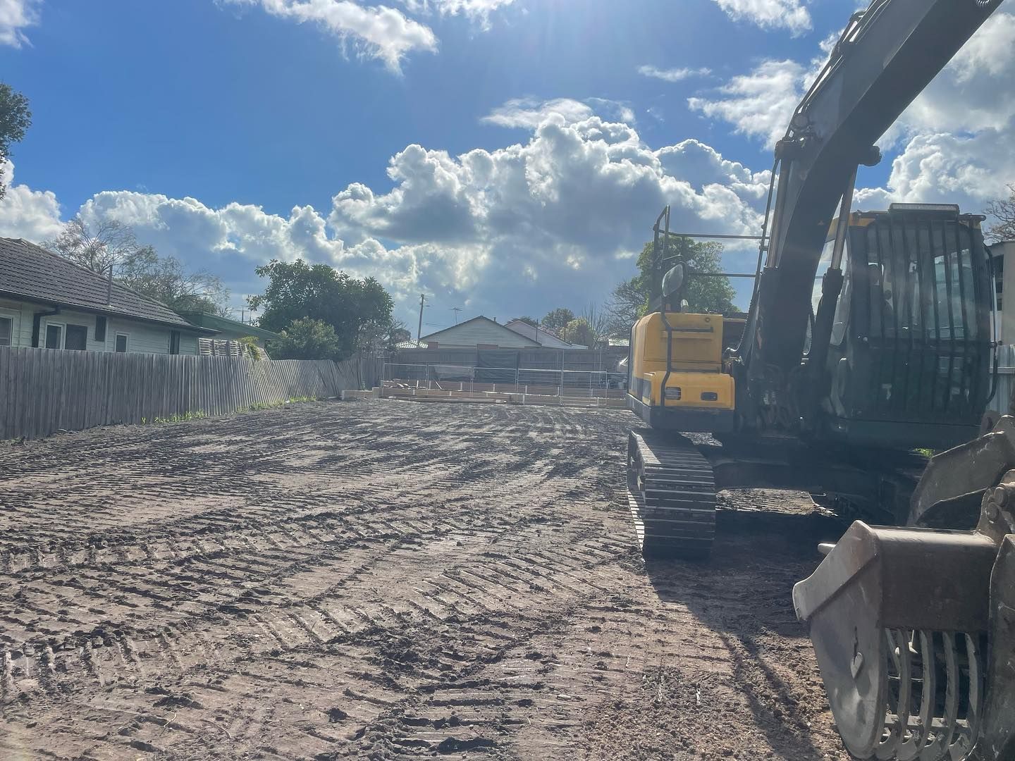 A large yellow excavator is working on a dirt field.