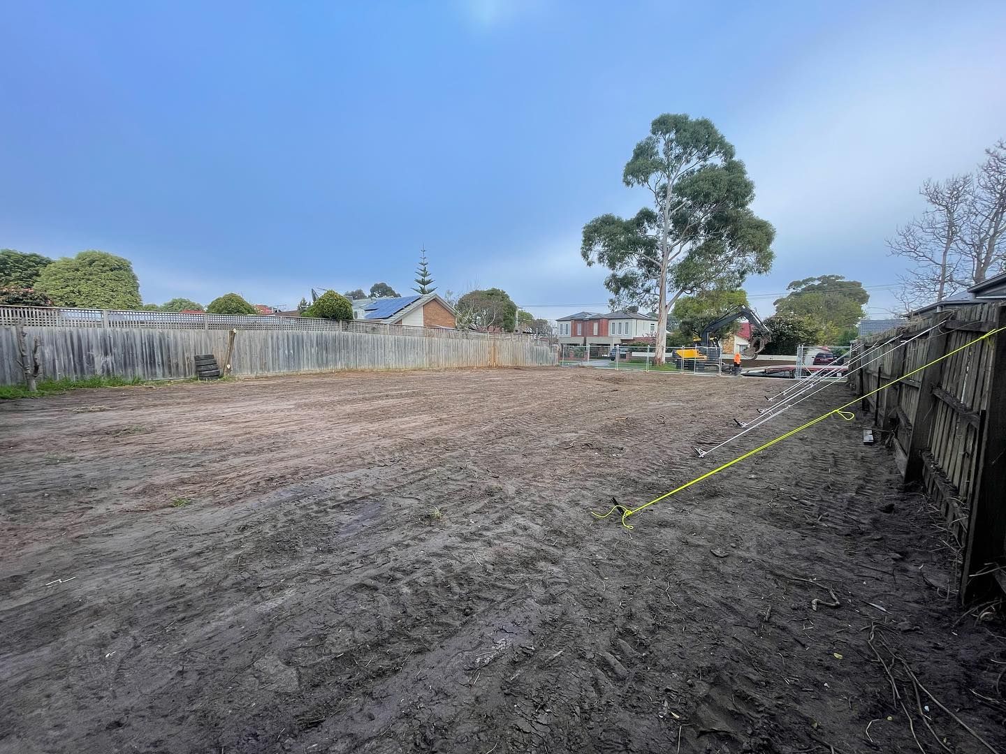 A large dirt field with a fence and trees in the background.