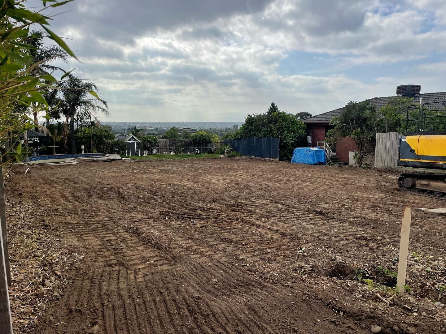 A large dirt field with a house in the background.