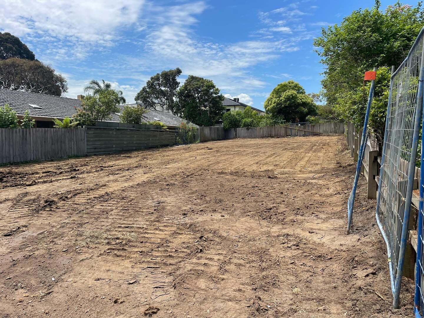 A dirt field with a fence and trees in the background.