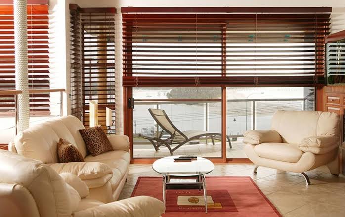 Living room with leather furniture, wood blinds, and a view of a waterfront.